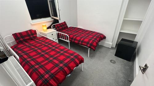 zwei Betten in einem Zimmer mit einer roten Decke in der Unterkunft Flexy Students Room 1 in Gloucestershire