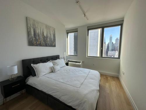 una camera da letto con un letto con lenzuola bianche e finestre di Time Square Condos a New York