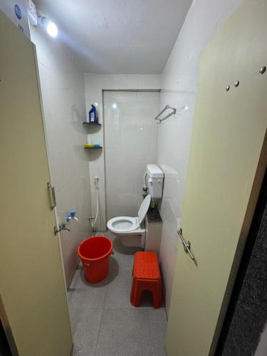 a small bathroom with a toilet and a red stool at Mahayaatri Niwas in Kolhapur