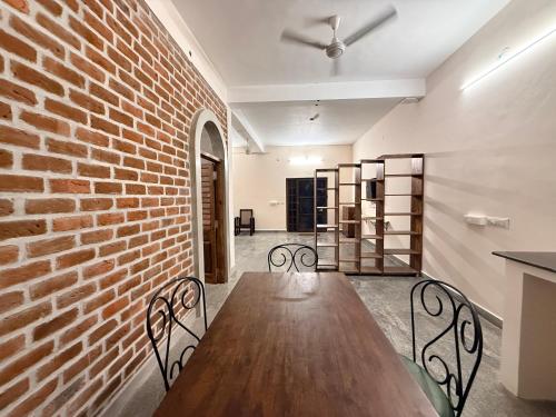 a room with a brick wall and a wooden table and chairs at Greens Heritage Resort with Swimming Pool in Auroville