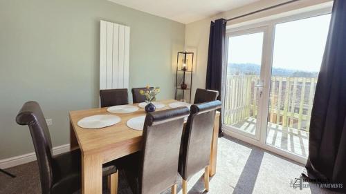 een eettafel met stoelen en een groot raam bij Modern & Spacious Flat with Balcony Views in Stroud