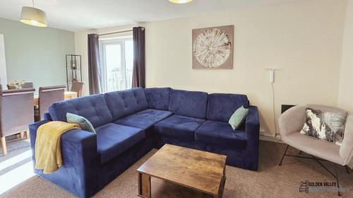 een woonkamer met een blauwe bank en een tafel bij Modern & Spacious Flat with Balcony Views in Stroud