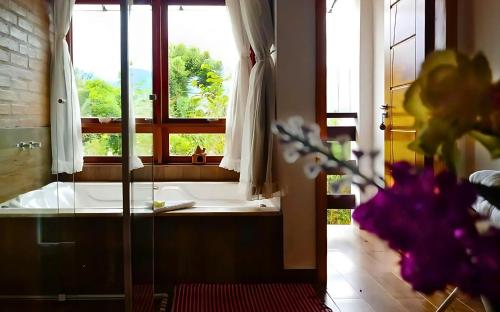 een badkamer met een bad en een raam bij Chalés Colline Verte in Monte Verde