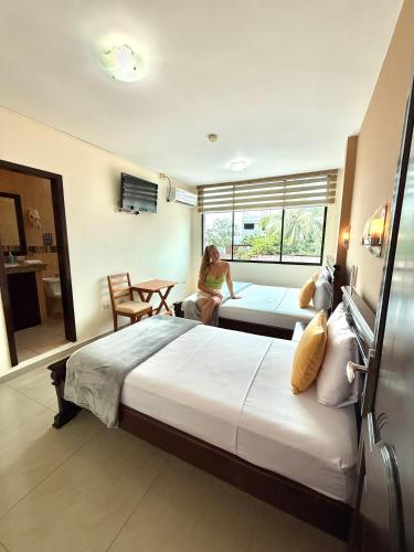 a woman sitting on a bed in a hotel room at Hotel Flamingo in Puerto Ayora
