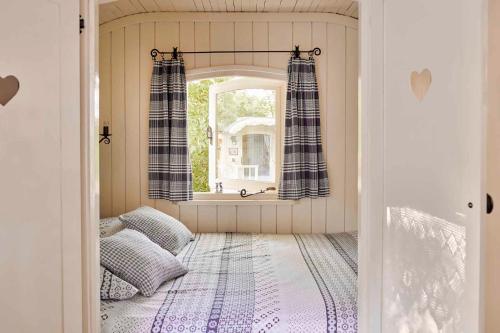 a room with a bed and a window in a room at Pipowagen de Luxe, prive hottub en zwembad in Heythuysen