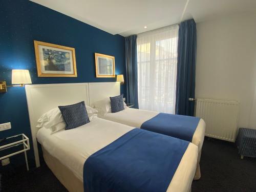 two beds in a hotel room with blue walls at Austin's Saint Lazare Hotel in Paris