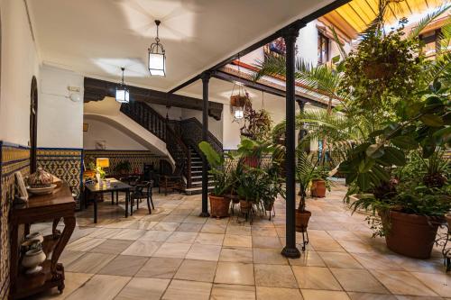 an indoor patio with plants and tables and chairs at Hotel Casa de los Azulejos in Córdoba