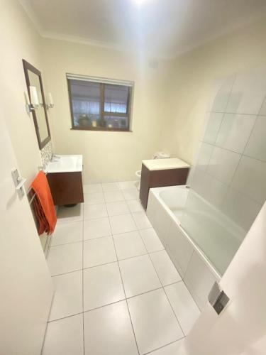 a white bathroom with a tub and a sink at On Point Tranquil Garden Constantiaberg in Sweet Valley