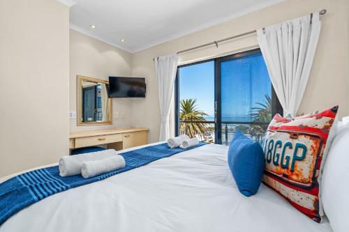 a bedroom with a large bed with a large window at Gordons Village View in Gordonʼs Bay