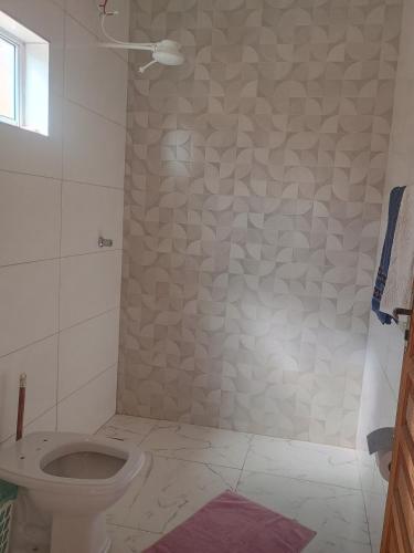 a bathroom with a toilet and a tiled wall at Espaço Dtalia in Piedade