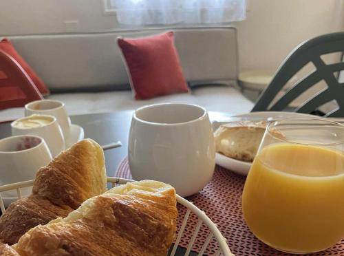 une table avec une assiette de pain et des verres de jus d'orange dans l'établissement Comme à la maison B and B, à Carcassonne