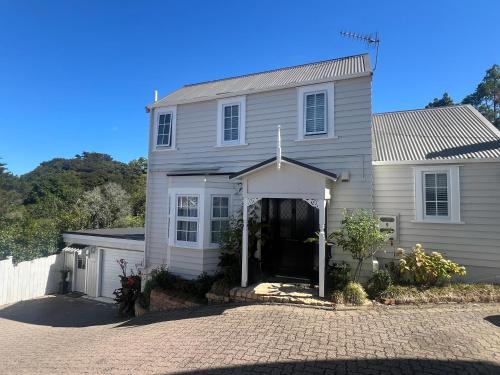 a white house with a driveway in front of it at Dove Cottage in Auckland