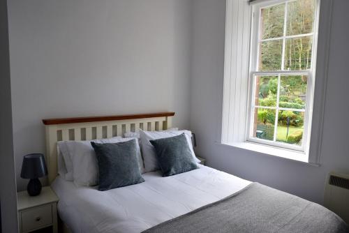 een slaapkamer met een wit bed met kussens en een raam bij Govandale Seaviews in Kingarth