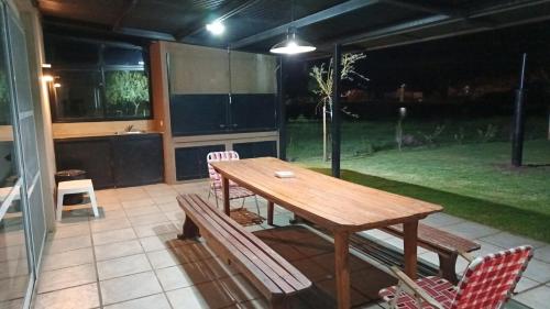 eine Terrasse mit einem Holztisch und einigen Stühlen in der Unterkunft Casa solares del carcaraña in Maciel