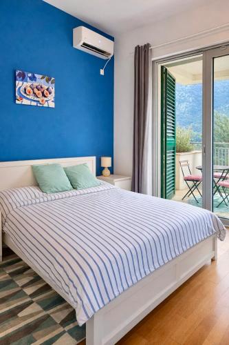 a bedroom with a bed with a blue wall at One-Bedroom Apartment with Terrace, Sea View, Pool and Spa Lavender Bay Morinj in Donji Morinj