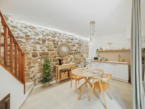 una cucina con un tavolo e un muro di pietra di L'Evasion Tropicale - idéal couple - sauna - baignoire balnéo LED - TV 4K Ambilight 130cm - parking gratuit à 2 pas du logement - wifi - maison médiévale sur 2 étages - entièrement rénovée 37m2 a Bargemon