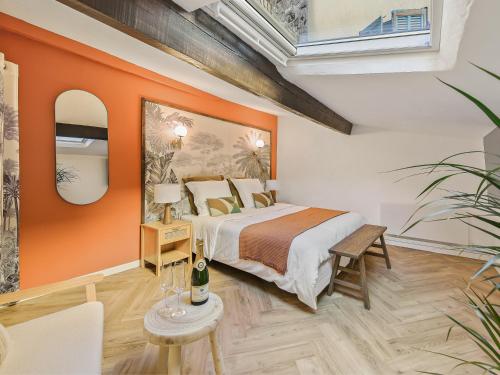 una camera con un grande letto con una parete arancione di L'Evasion Tropicale - idéal couple - sauna - baignoire balnéo LED - TV 4K Ambilight 130cm - parking gratuit à 2 pas du logement - wifi - maison médiévale sur 2 étages - entièrement rénovée 37m2 a Bargemon
