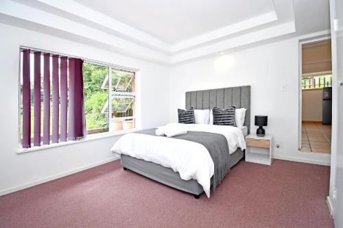 een witte slaapkamer met een groot bed en een raam bij Sandton Elite Stay in Sandton