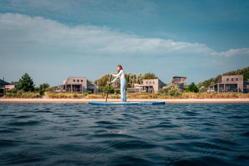 a person standing on a paddle board in the water at Beach Resort Punt West in Ouddorp