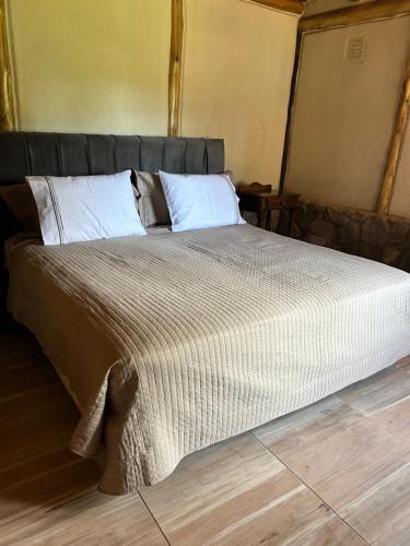 a bedroom with a large bed with white pillows at Cabañas del Pasaje in Las Compuertas