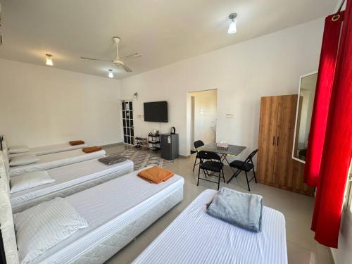 a room with four beds and a table and a tv at Gisa Hostel All Private Ensuite Rooms in Mawāliḩ