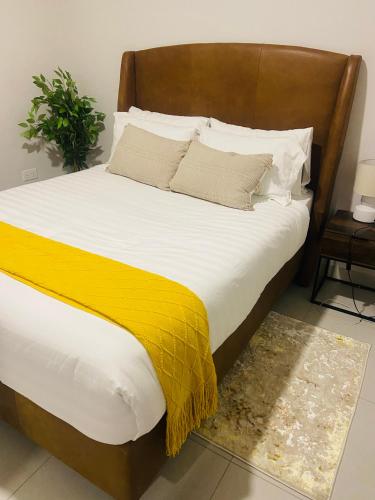 łóżko z drewnianym zagłówkiem i żółtym kocem w obiekcie Kadzi Edge w mieście Gaborone