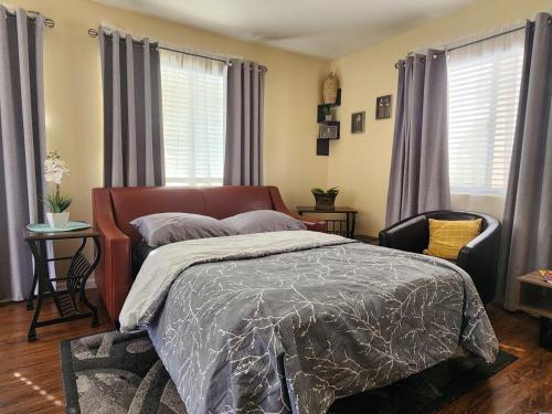 a bedroom with a bed and a chair and windows at Charming 1-bed apt, cook-ready kitchen, laundry, 5-8 mins to U of A and Downtown in Tucson