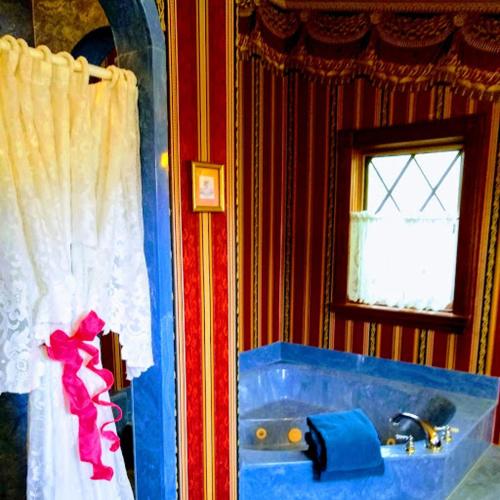 a bathroom with a blue tub and a window at Shamrock Thistle & Crown B&B in Weirsdale