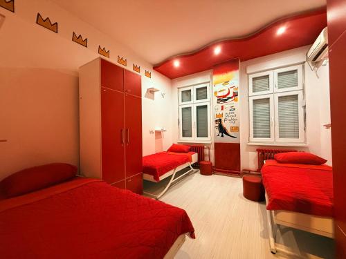 een kamer met twee bedden met rode dekens en ramen bij Pop Art in Belgrado