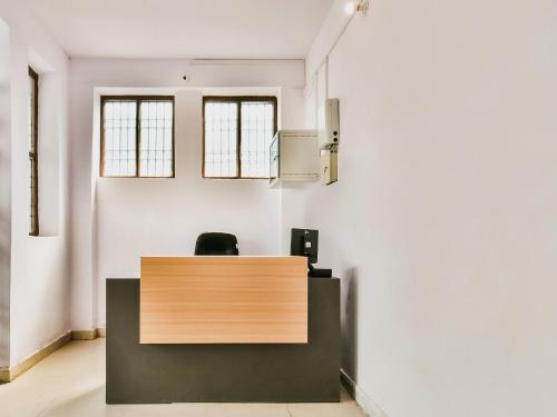 ein Büro mit einem hölzernen Empfangstresen mit zwei Fenstern in der Unterkunft Hotel O AG Colony Park Patna Formerly Capital Pearl in Patna