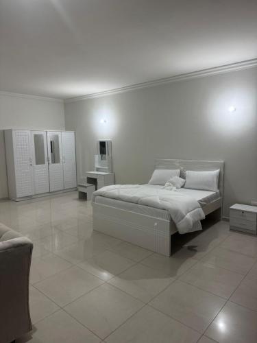 a white bedroom with a bed and a tiled floor at SN REAL ESTATE HOME in Abu Dhabi