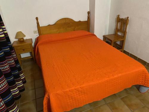 un letto con piumone arancione in una camera da letto di Casa Alta 14 B a Palanques