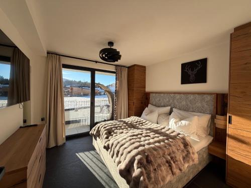 a bedroom with a large bed and a large window at Alpen Sky Suite Flachau in Flachau