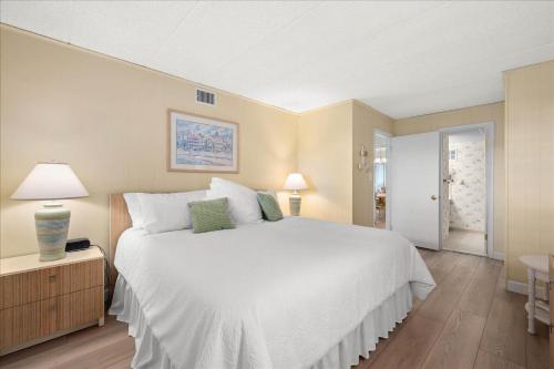 a bedroom with a large white bed and a table at 2 Bedroom Ocean Block Condo, Steps to the Beach! in Ocean City