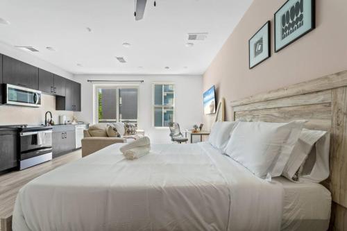 a bedroom with a large white bed and a kitchen at Chic Channelside Studio | Perfect Gate Away! in Tampa