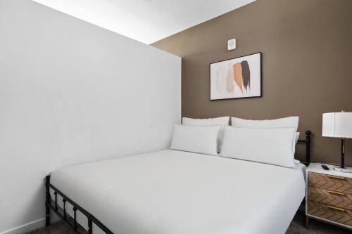een slaapkamer met een groot wit bed met een witte sprei bij Premium Downtown High-Rise Condo with Pool, Parking, Gym in Indianapolis