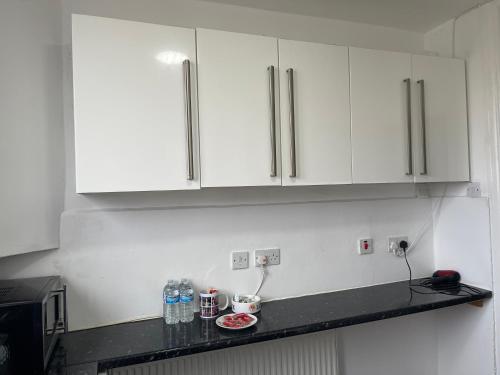 a kitchen with white cabinets and a black counter top at Kingsbury Service Accommodation in Colindale