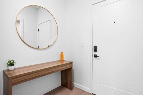 een spiegel aan een muur naast een houten tafel bij The Indy Suite High-Rise Condo with Pool, Gym, Parking in Indianapolis