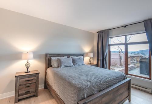 a bedroom with a bed and a large window at Altitude Ski-in Out at Resort with Private Hottub in Mont-Tremblant