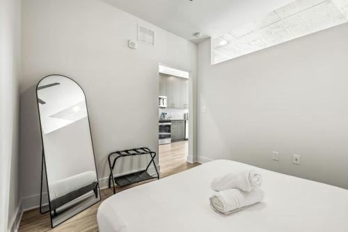 a white bedroom with a bed and a mirror at Chic Channelside Getaway in DT | Close to DT! in Tampa