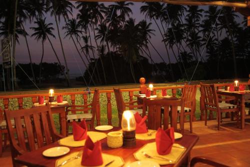 a table with candles and chairs on a deck at Prince Beach Hotel Bentota in Bentota