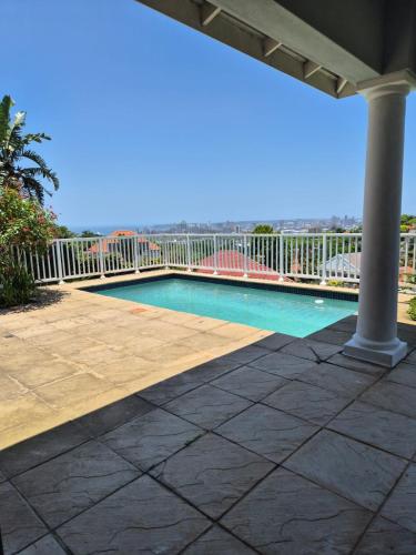 een zwembad op een patio met een balkon bij Holland Manor in Durban