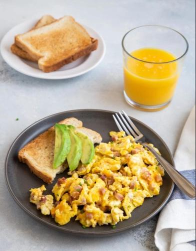 een bord eieren en toast en een glas sinaasappelsap bij Casa Luna Hotel in Taganga