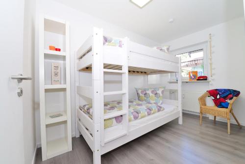 een wit stapelbed in een kamer met een stoel bij Haus Ideal 3-Raum-Wohnung edelWEISS in Fischen