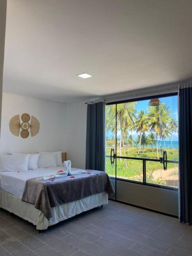 a bedroom with a bed and a large window at Pousada Canouan in Japaratinga