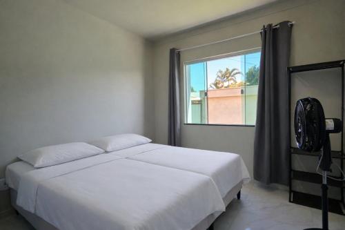 a bedroom with a white bed and a window at Casa privativa em Itaúna in Saquarema