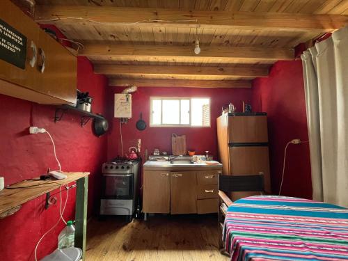 a kitchen with red walls and a sink and a stove at Luna & Zoé in Barra de Valizas