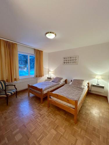 a bedroom with two beds and a chair at Sorecrans in Crans-Montana
