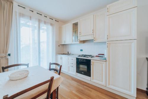 una cucina con mobili bianchi e un tavolo e una sala da pranzo di Ohana a Montecchio Maggiore