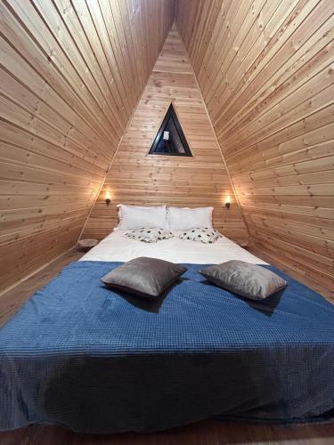 a bed in a wooden room with two pillows on it at A Frame la Iaz in Mărăcineni